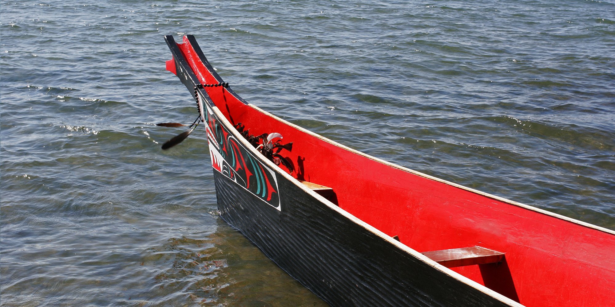 black and red painted canoe on water